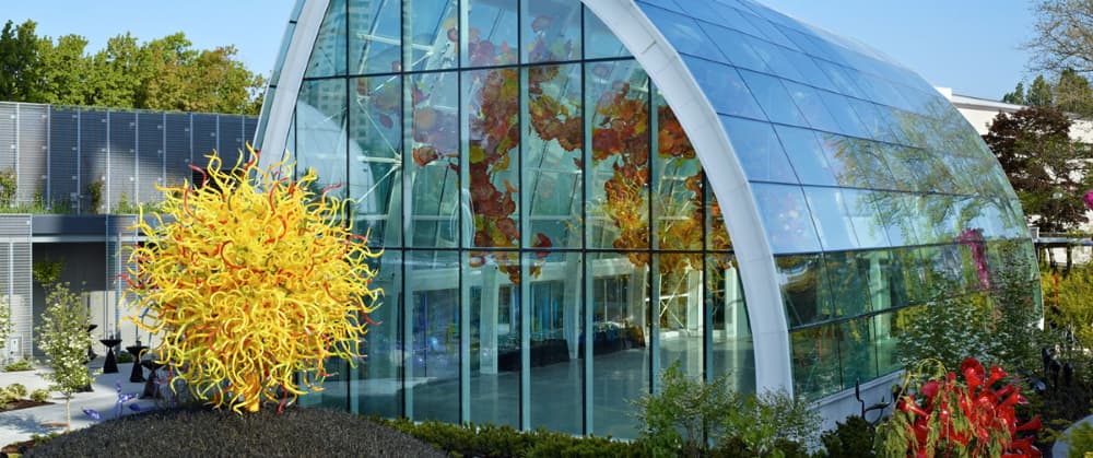 Glass-and-steel glasshouse exterior at dusk